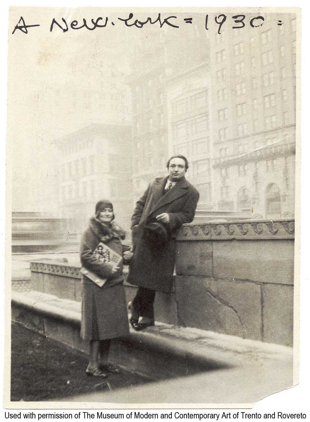 Dep.6.3.8 - «A New York - 1930». - New York, 1930. - 1 fotografia : b.n. ; 110 x 85 mm Pubblicato in: R. Antolini (a cura di), «Libri taglienti esplosivi e luminosi», 2005, p.134. Precedente segnatura Vol.850,|p.6 Sommario: Depero e Rosetta, con il libro imbullonato in mano, a New York sul tetto dell'Advertising Club in Park Avenue